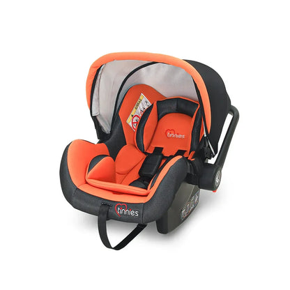 Orange and black baby car seat with 'tinnies' branding on a white background