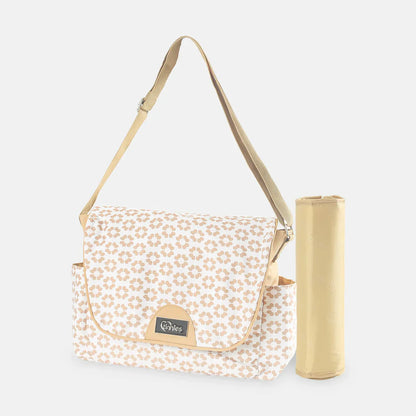 Patterned bag with a strap and a cylindrical gold product on a white background